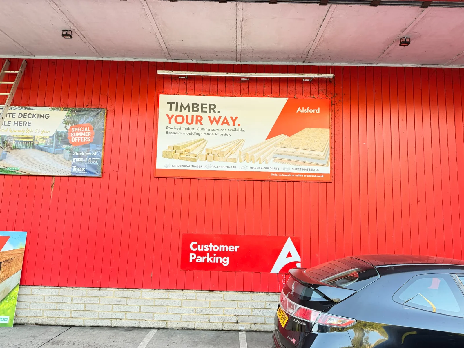 Alsford campaign billboard on red cladding beneath a covered roof