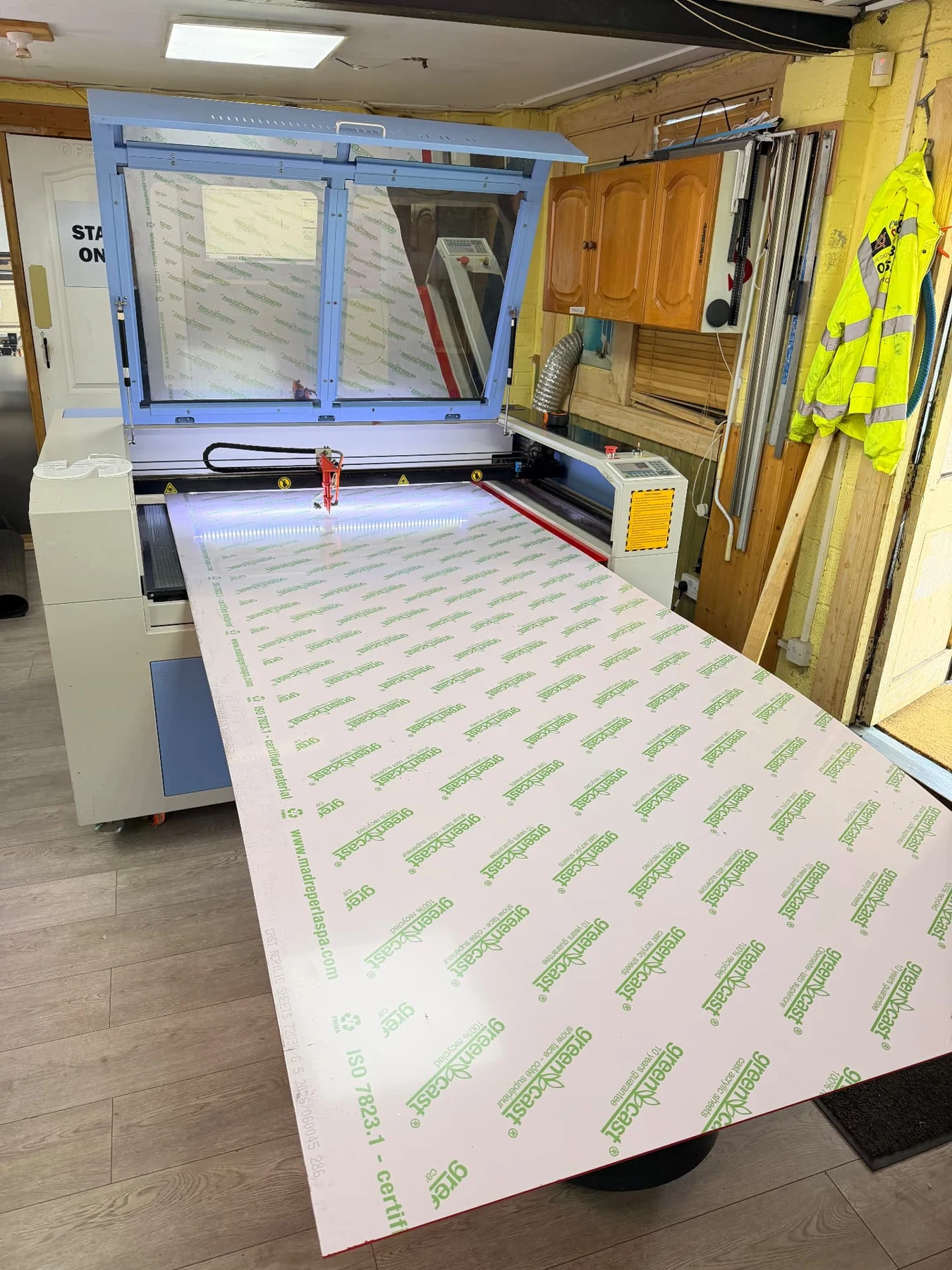 Oversized acrylic sheet with protective masking positioned through the workshop laser