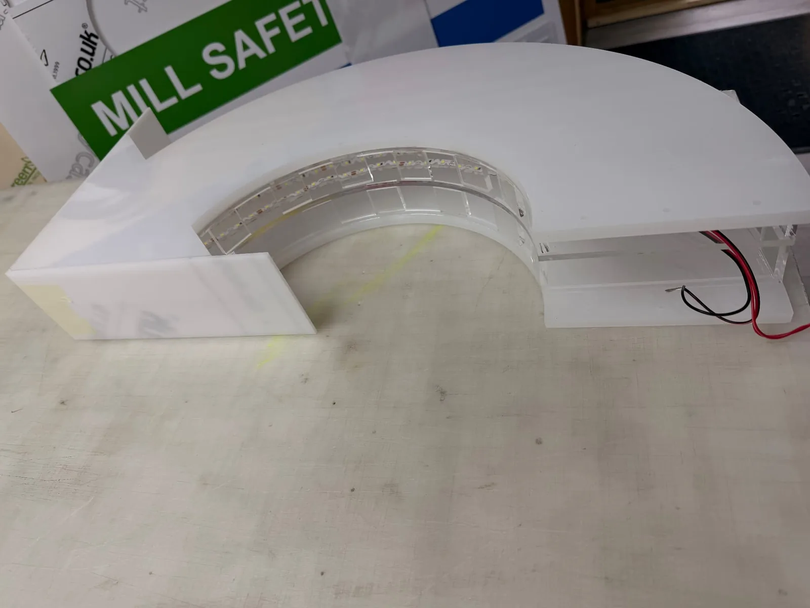 Close-up of the curved acrylic arrow construction with internal LED modules and wiring visible