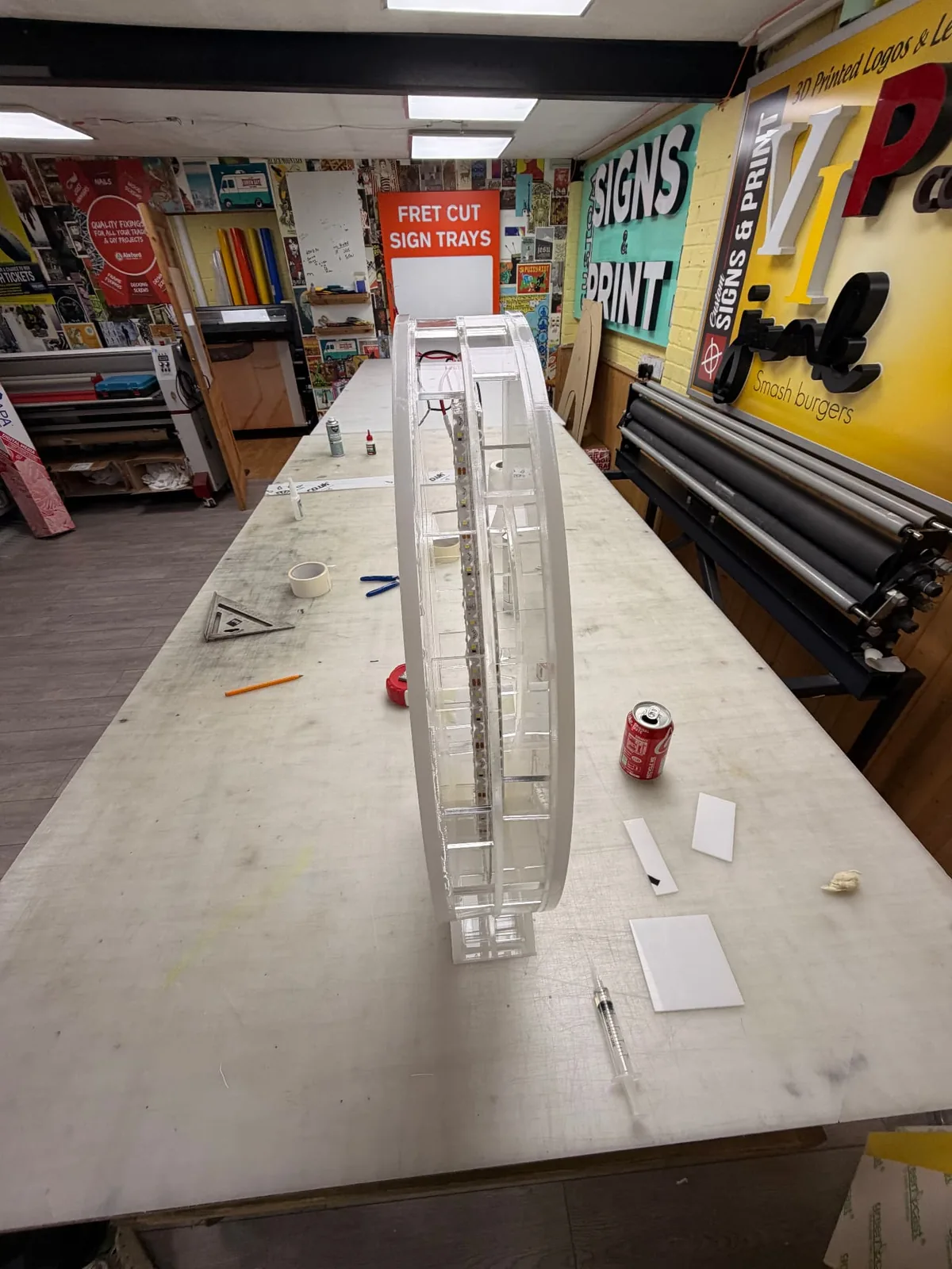 Clear acrylic arrow stood on edge on a long workbench, showing its depth and internal structure