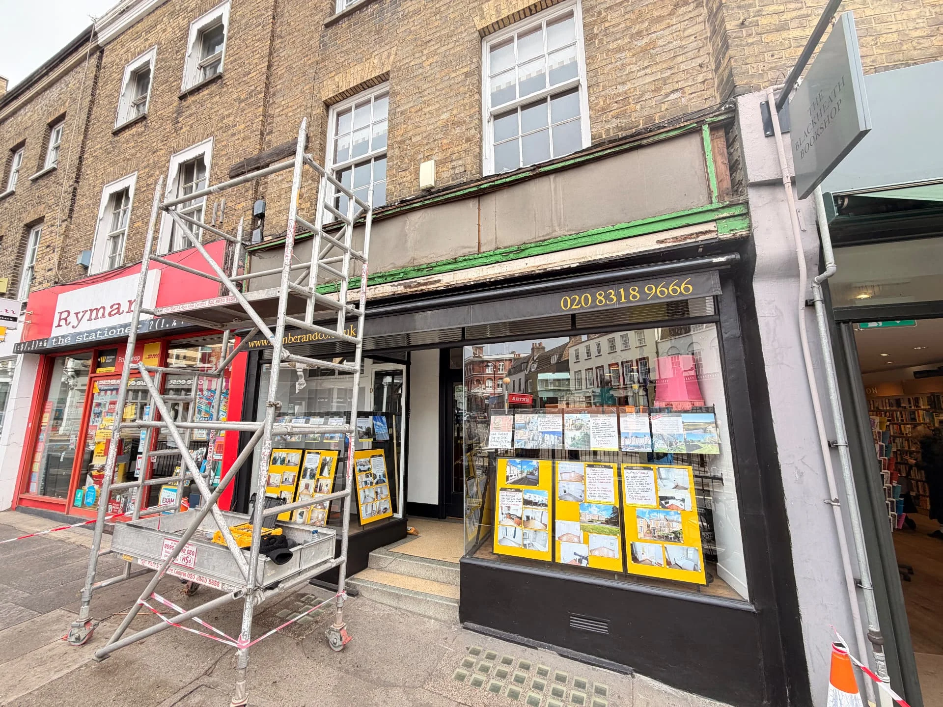 Strip-down stage at Comber & Co: old fascia removed with underlying backing and framework exposed, and access scaffolding in front