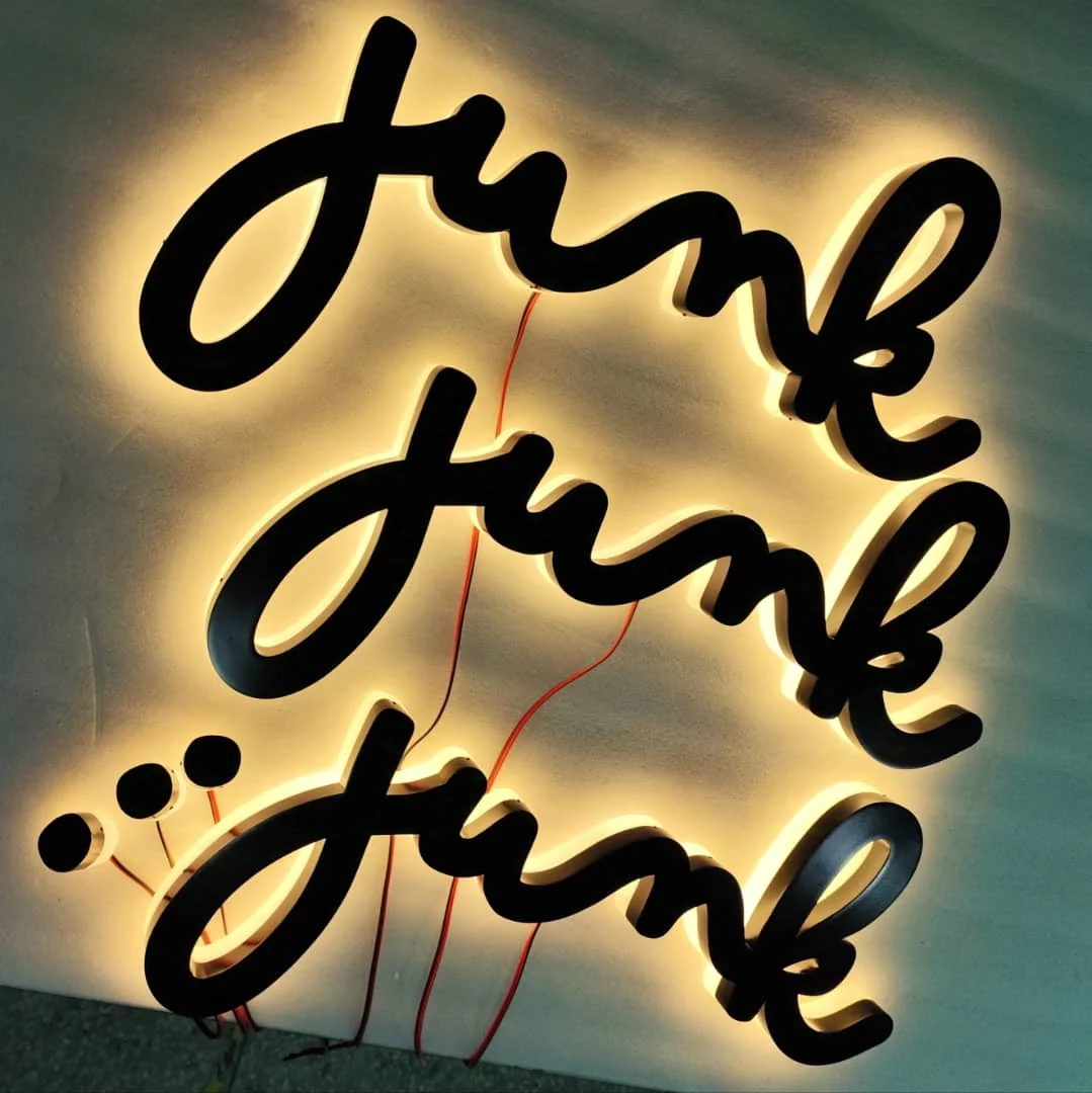 Three sets of halo-lit Junk script letters being tested on the bench in our workshop