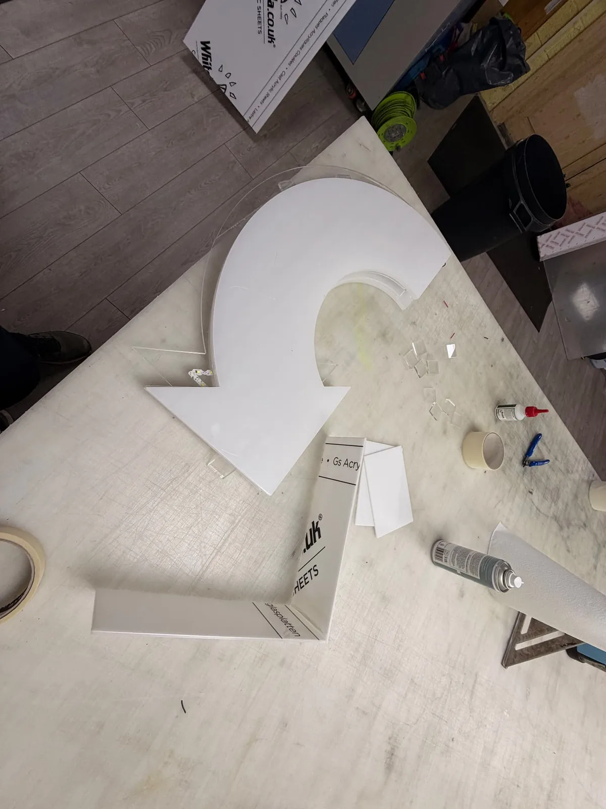 White acrylic arrow pieces and returns being assembled on a workshop bench