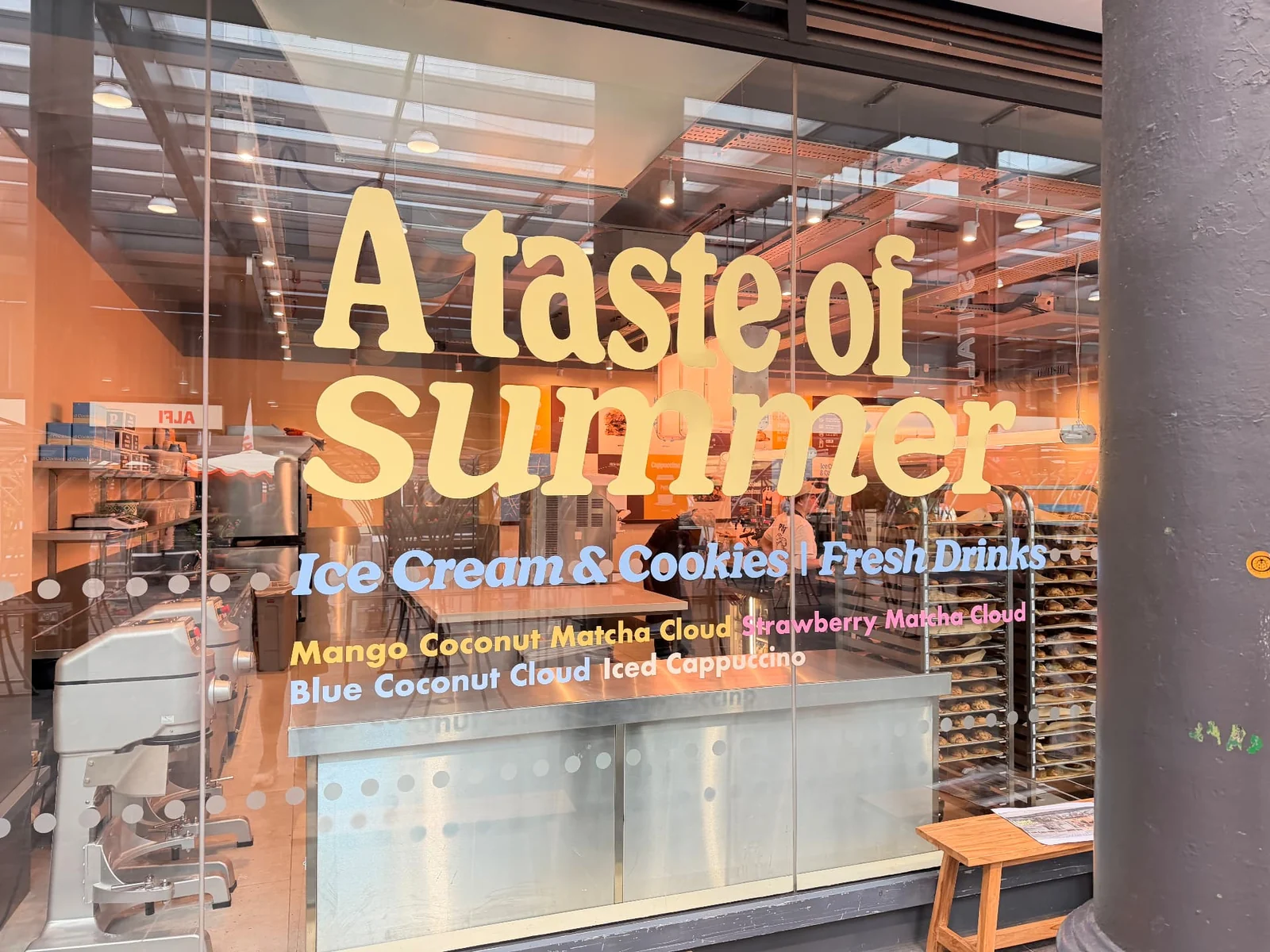 Puffy window graphics in pale yellow, blue and pink cut vinyl with circular manifestation dots across the glazing