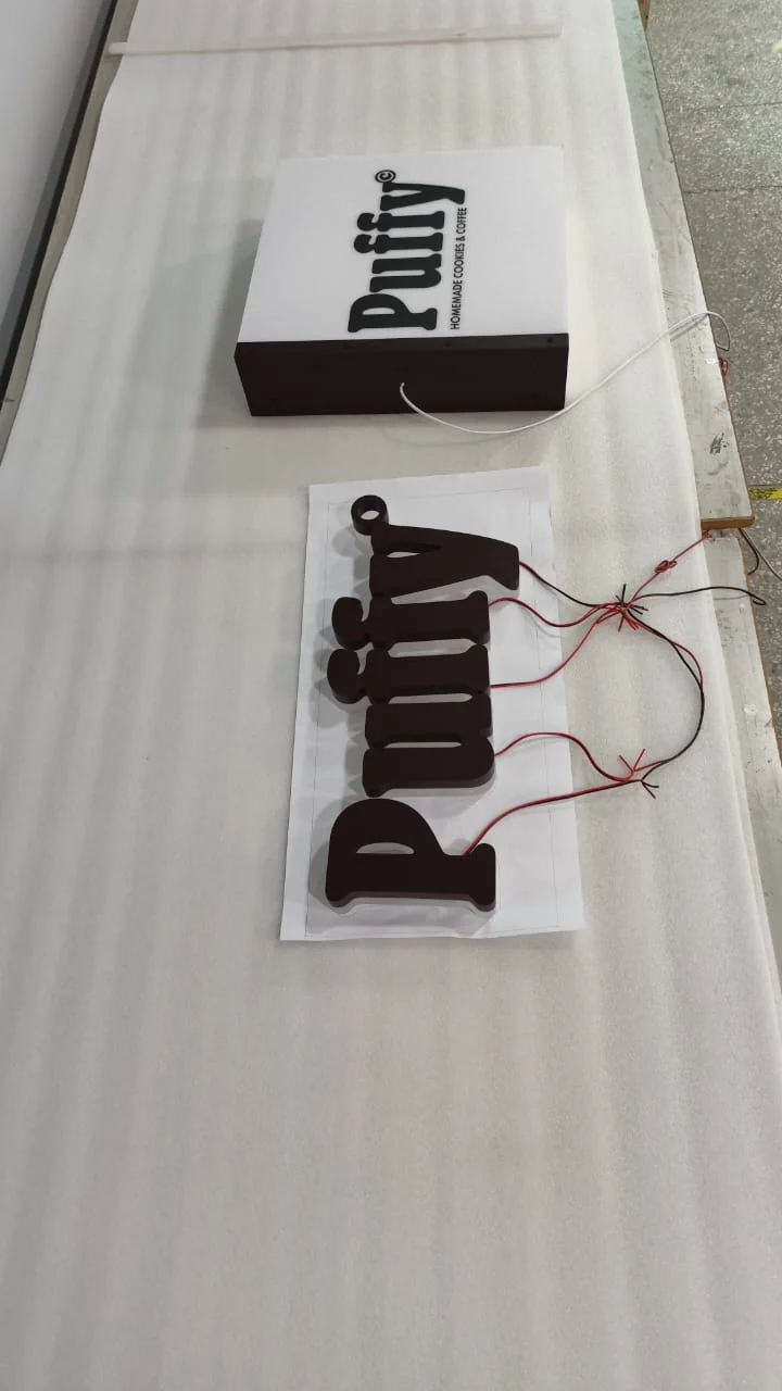 Puffy lightbox and wired 3D letters laid out on a workbench in our workshop during assembly