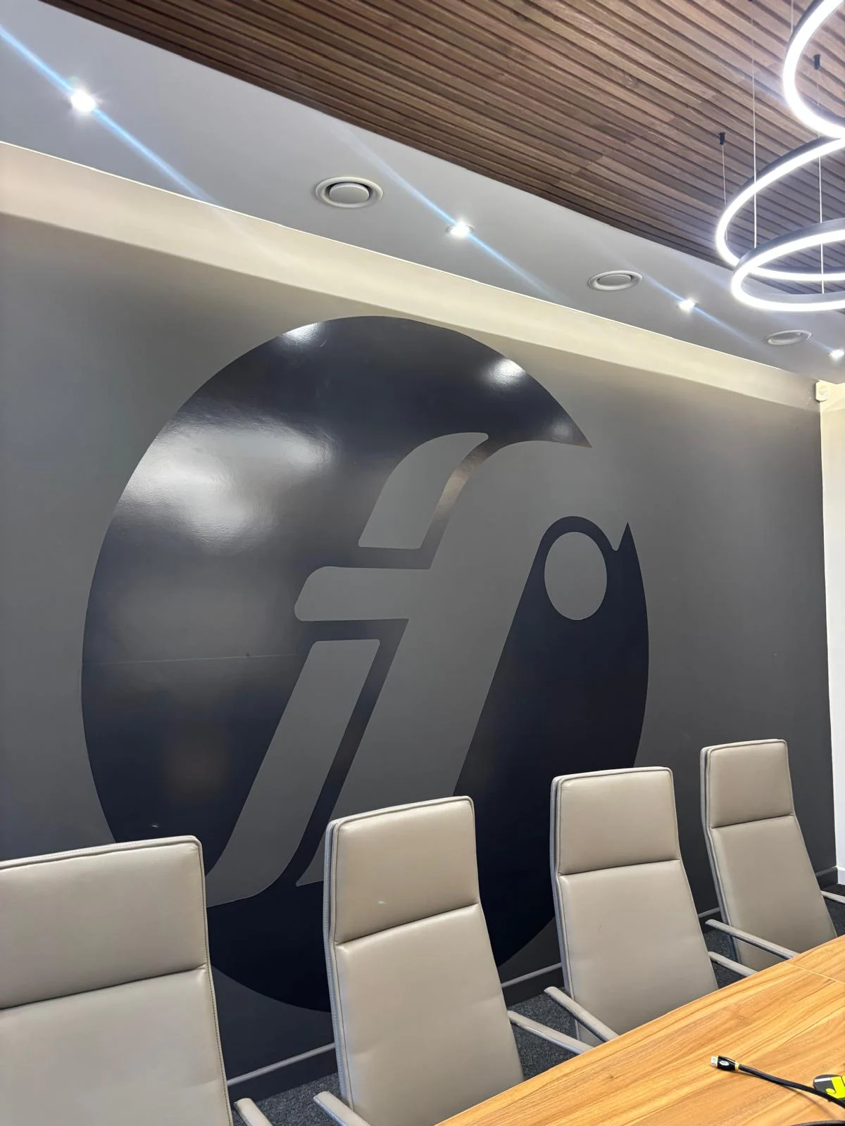 Large dark Fixmart logo wall decal behind the boardroom table and chairs