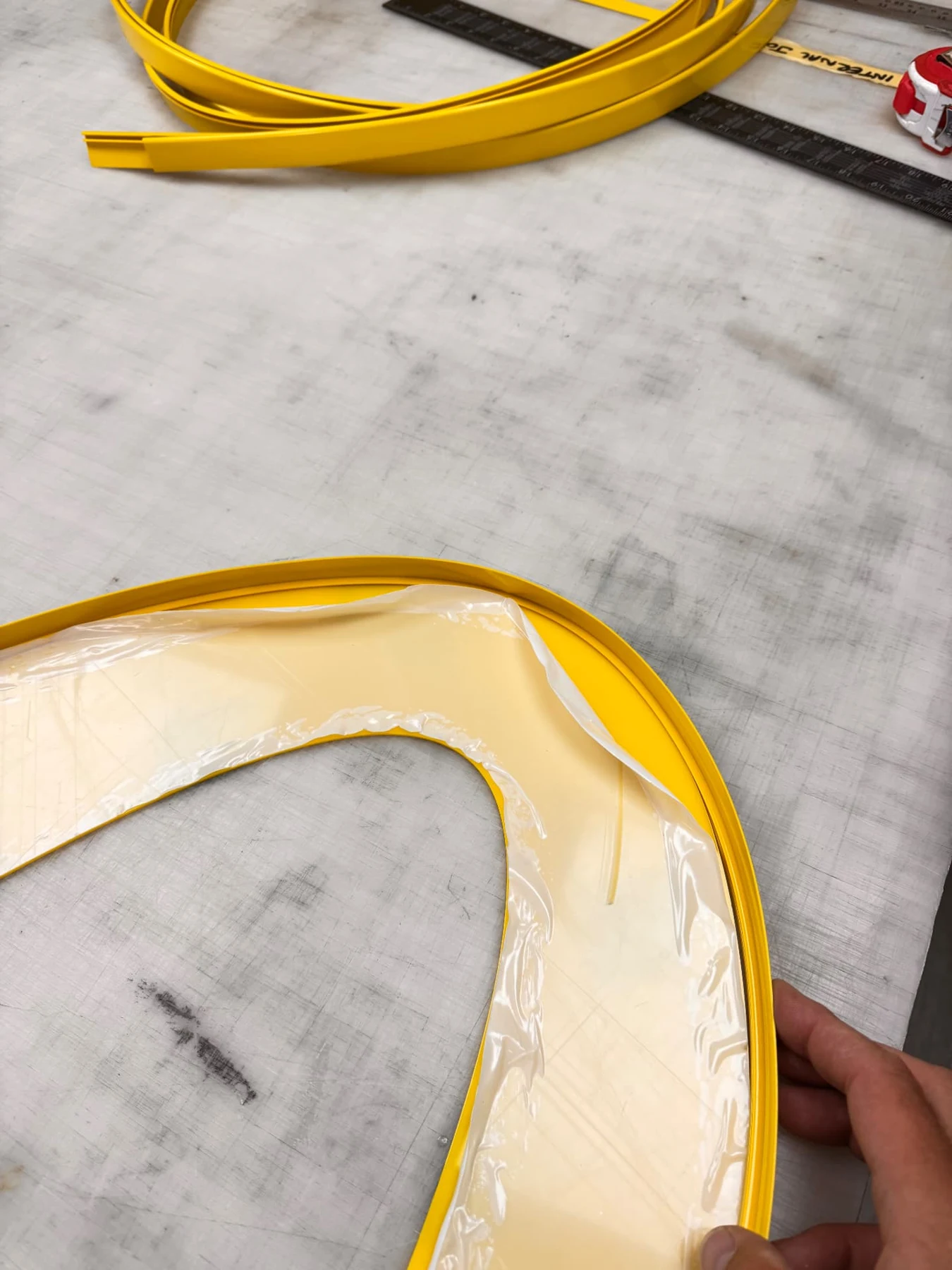 Close-up of yellow edging being hand fitted around the curve of an acrylic arch