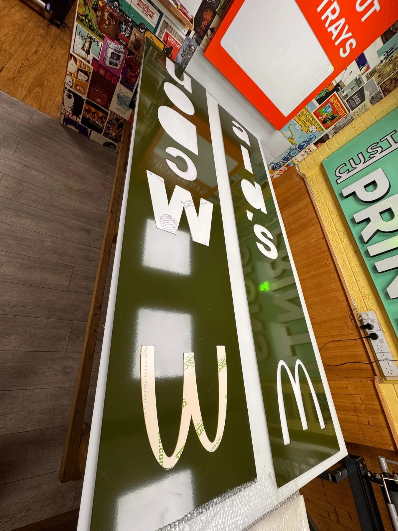 Green sign faces with fitted acrylic lettering laid out in the workshop