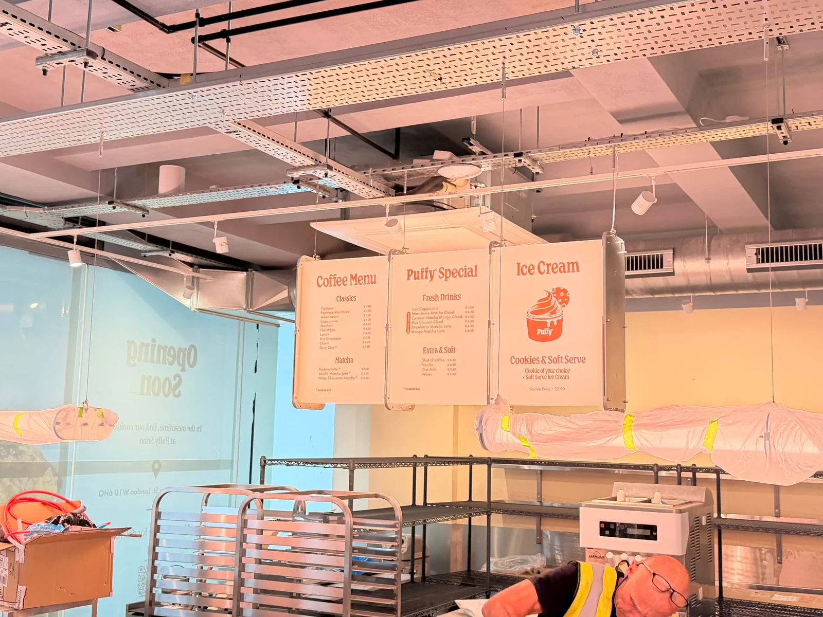 Three suspended Puffy illuminated menu boxes above the counter, with window vinyl visible beyond