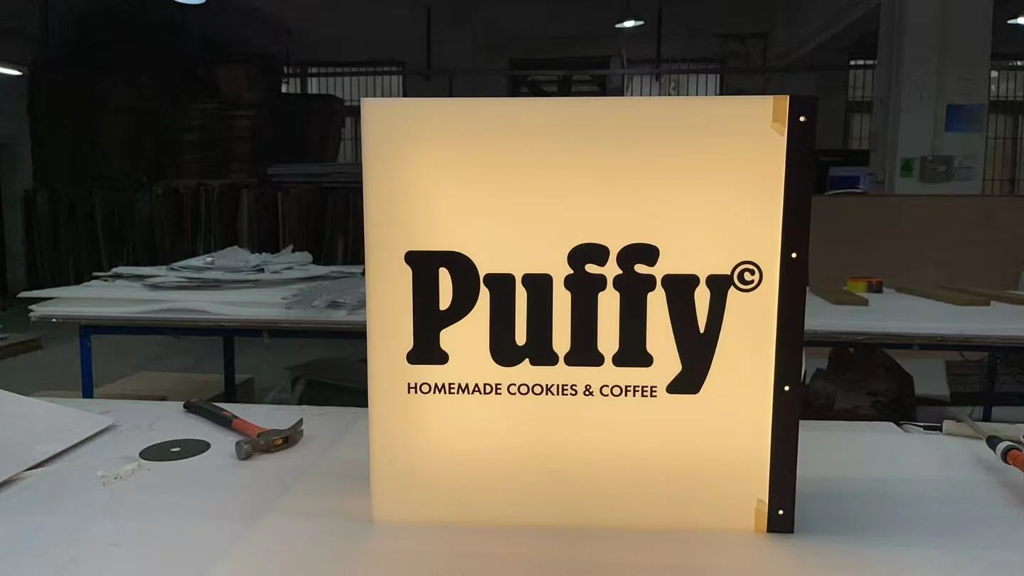 Puffy lightbox sign powered on beside hand tools on a workshop production bench