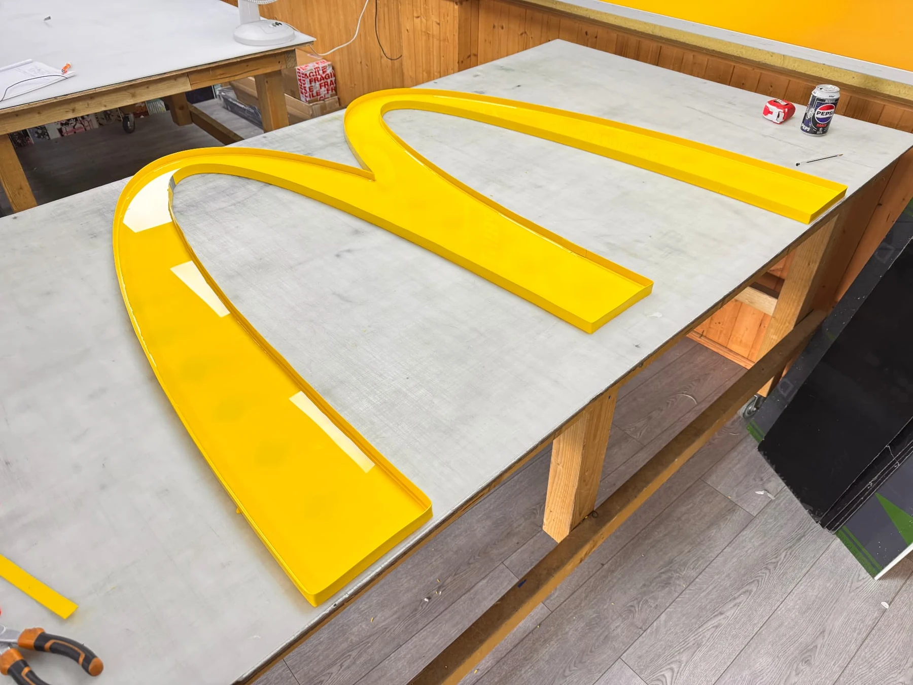 Assembled yellow acrylic arches with fitted edging lying on a workshop bench